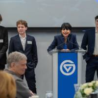 President Mantella speaking at podium with GVSU students on stage